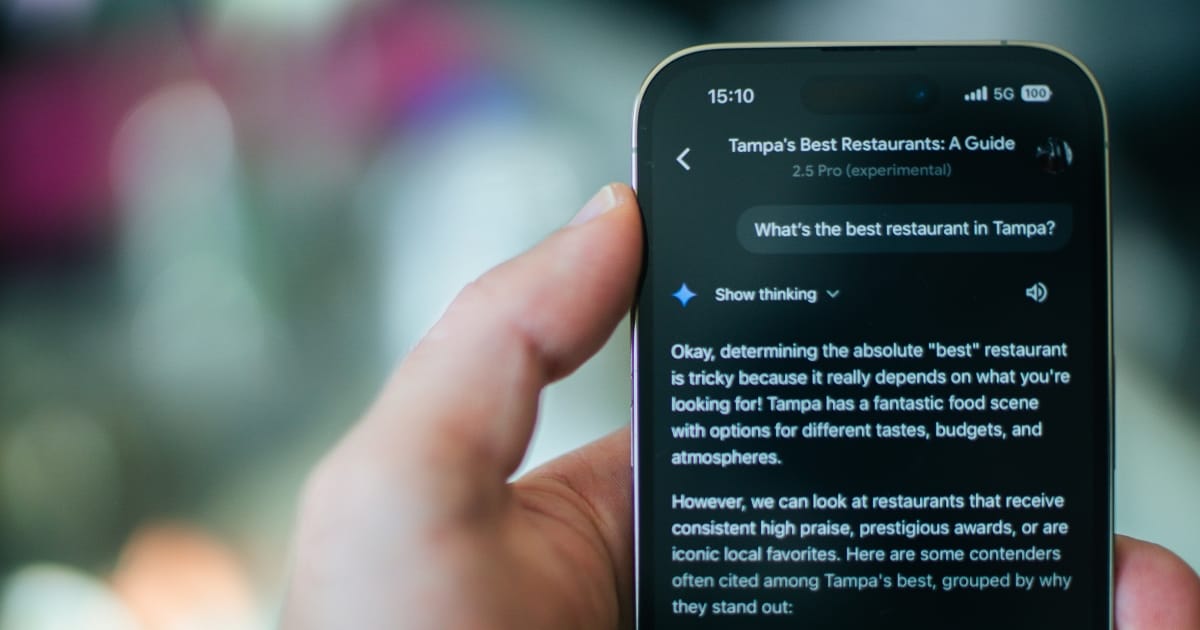 En person håller i en smartphone som visar en app för att söka restauranger i Tampa, vilket definierar ZORC:s AI-funktioner